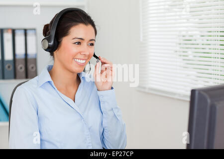 Lovely woman with a headset helping customers while sitting Stock Photo
