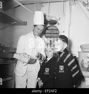 Mrs Sterry and her two children visit Mr Sterry, who works as an assistant crew cook on the 'Bloemfontain Castle' motor vessel. Mrs Sterry asked the Daily Mirror to photograph her husband with the ship in the background, as he was due to be transferred when the ship was sold to the Greeks. The Daily Mirror went one better and invited the family to visit the ship and toy fair at Kensington High Street. Picture Shows Mr Sterry presenting his children, Susie and Richard with a Yacht that he brought them back from South Africa. 12th November 1959. Stock Photo