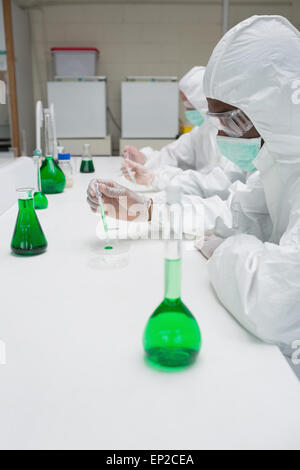 Chemists in protective suits working with green chemical Stock Photo