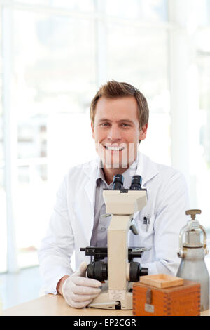 Male scientist looking at a slide under a microscope Stock Photo