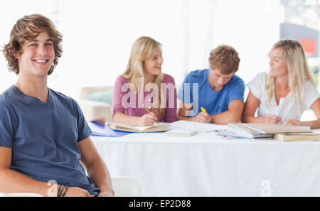 Smiling man sitting on front of his friends and looking at the camera Stock Photo