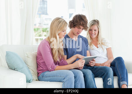Borther and sisters sit on the couch while looking at a tablet pc Stock Photo