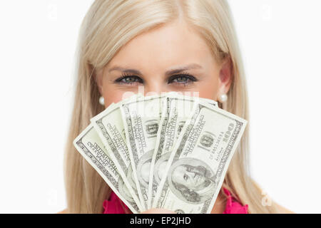 Smiling blonde hiding her face with 100 dollars banknotes Stock Photo