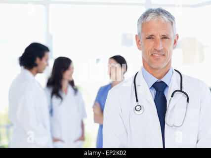 Mature and calm doctor standing upright in front of his medical interns Stock Photo