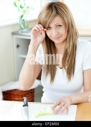 Pretty young woman cutting onions and crying in the kitchen Stock Photo