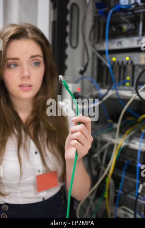 Woman holding green wire of server and looking confused Stock Photo