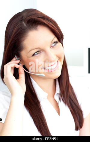 Smiling businesswoman talking on phone using headphones in her office Stock Photo