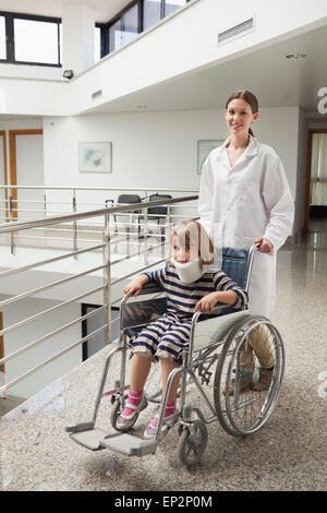 Child in neck brace being pushed in wheelchair by doctor Stock Photo