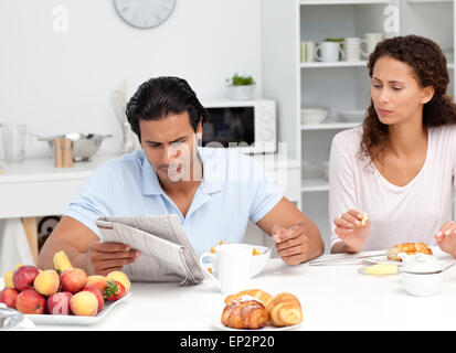 Concentrated couple reading the newspaper together during breakfast Stock Photo