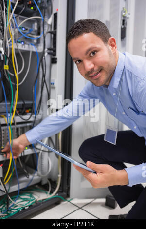 Technician plugging in cables and using tablet pc Stock Photo