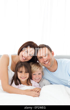 Portrait of a joyful family sitting on the bed Stock Photo