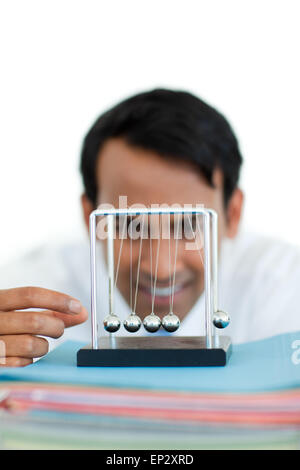 Ethnic businessman playing with kinetic balls Stock Photo