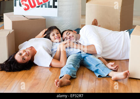 Family in a new house lying on floor with boxes Stock Photo