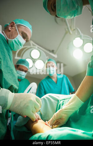Team of surgeons using scalpel to open a patient Stock Photo