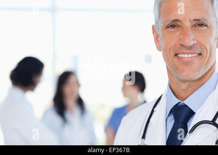 Smiling doctor with his medical interns behind him Stock Photo