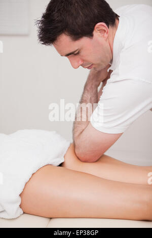 Chiropractor massaging the thigh of his patient while using his elbow Stock Photo