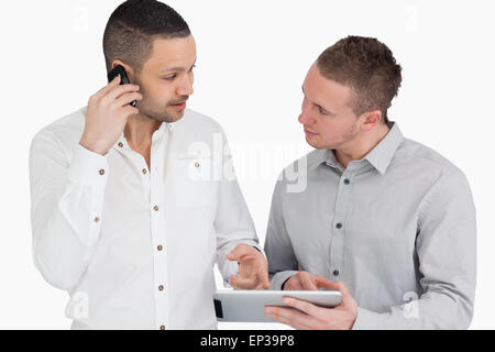 Two people discussing while phoning and holding a tablet computer Stock Photo