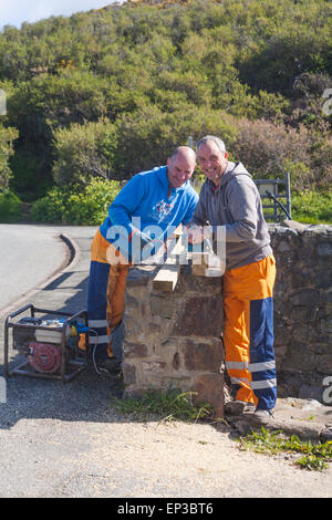 Workmen sawing through plank of wood at Porthclais harbour near St Davids at Pembrokeshire Coast National Park, Wales UK in May Stock Photo