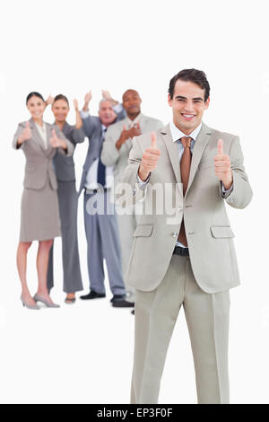 Smiling businessman with team behind him giving thumbs up Stock Photo ...