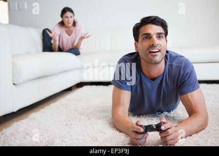 Man playing video games while his fiance is getting mad at him Stock Photo