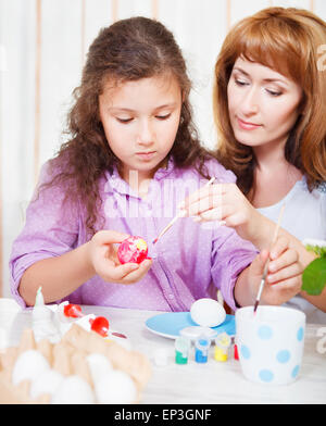 Mother and her little daughter painting on Easter eggs Stock Photo