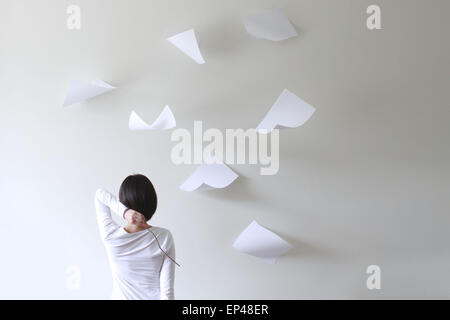 Rear view of a woman holding a stick behind her head with pieces of paper flying around Stock Photo