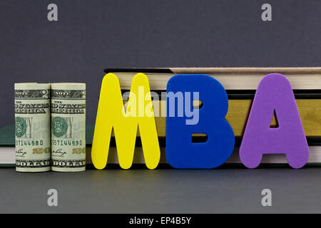 Graduate degree MBA letters with dollar currency in front of books on gray background. Stock Photo