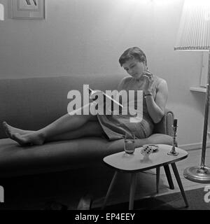 Junge Ruth Drasy liegt in ihrem Wohnzimmer auf dem Sofa, Deutschland 1950er Jahre. Young Ruth Drasy lying on the sofa at her