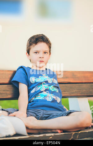sad boy sitting on a bench Stock Photo