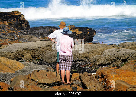 Elderly couple enjoying a walk along the rocky shoreline in seaside village of Scarborough near Cape Town, South Africa. Stock Photo