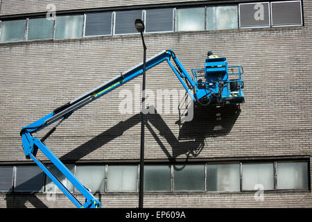 Hydraulic lift working above high up repairs wall Stock Photo
