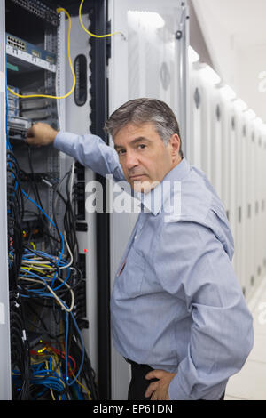 Technician looking up from adjusting server wires Stock Photo