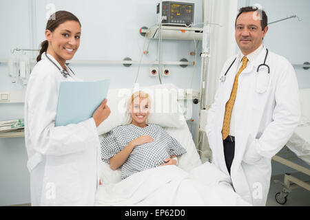 Female and male doctor standing next to a woman patient Stock Photo