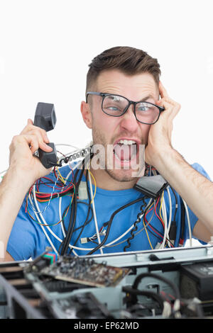 Frustrated computer engineer screaming while on call in front of open cpu Stock Photo