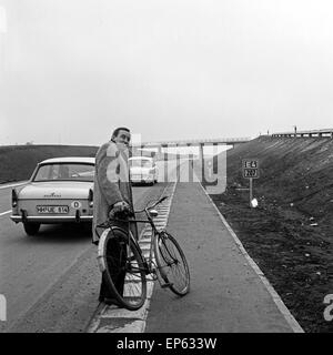 Ein Mann mit einem Fahrrad auf dem Seitenstreifen der E4, Deutschland 1960er Jahre. A man with his bicycle at the verge of E4 hi Stock Photo