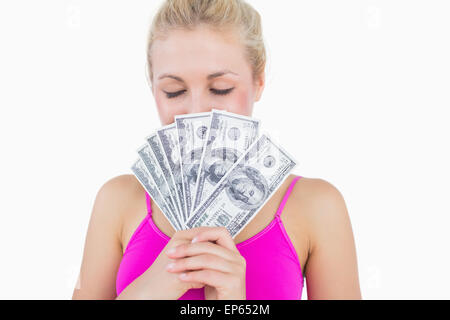 Woman holding fanned banknotes in front of face with eyes closed Stock Photo