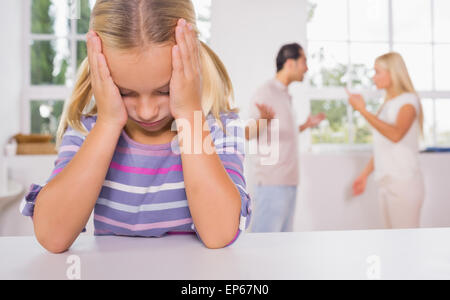 Little girl looking depressed in front of fighting parents Stock Photo
