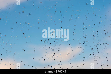 Raindrops on a window pane infront of a blue sky Stock Photo