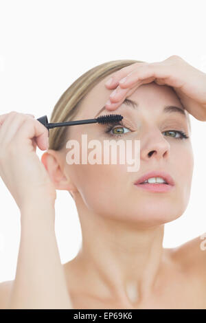 Closeup portrait of young woman applying mascara to her eye Stock Photo