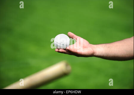 Hand holding a rounders ball. Rounders is a bat and ball game between two team that involves hitting a hard leather cased ball w Stock Photo