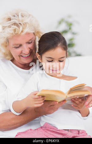 Granddaughter and grandmother reading a novel together Stock Photo