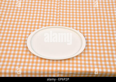 White porcelain plate set on a yellow-white tablecloth Stock Photo