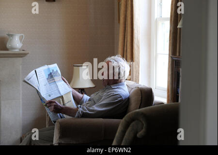 Elderly pensioner reading the Daily Telegraph at home in North Yorkshire. Stock Photo