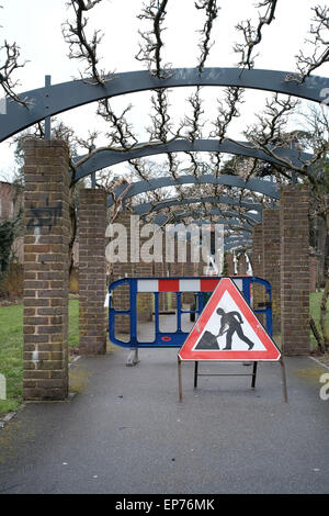 Men at work sign putting wisteria flowers in Southampton park pergola Stock Photo