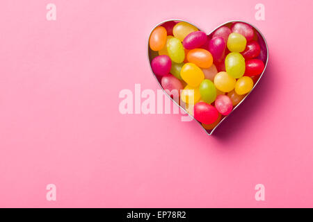 heart made from jelly beans on pink background Stock Photo
