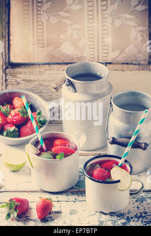 Vintage metal cups with retro cocktail tubes and water-cans of homemade strawberry lemonade, served with fresh strawberries, min Stock Photo