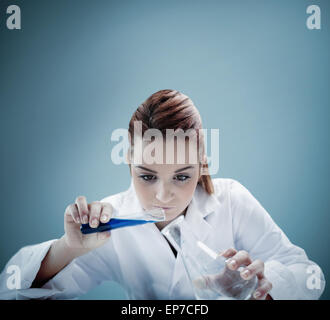 Blonde scientist pouring liquid into erlenmeyer Stock Photo