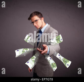 Young man standing and throwing money Stock Photo