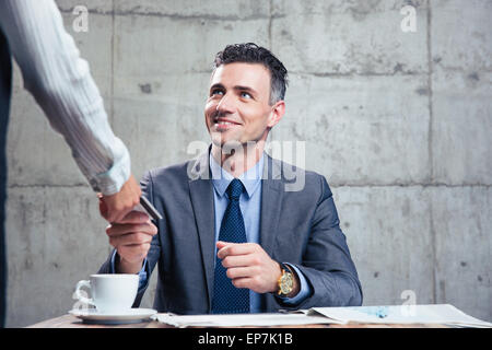 Smiling man giving bank card to female waiter in restraurant Stock Photo
