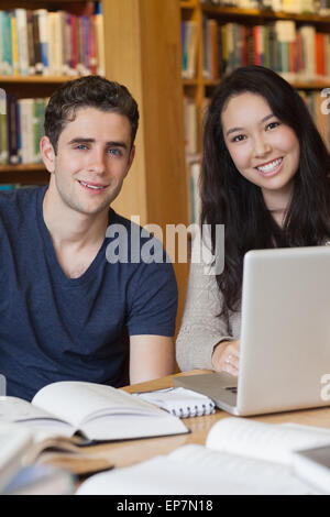 Two students learning with a laptop in a library Stock Photo
